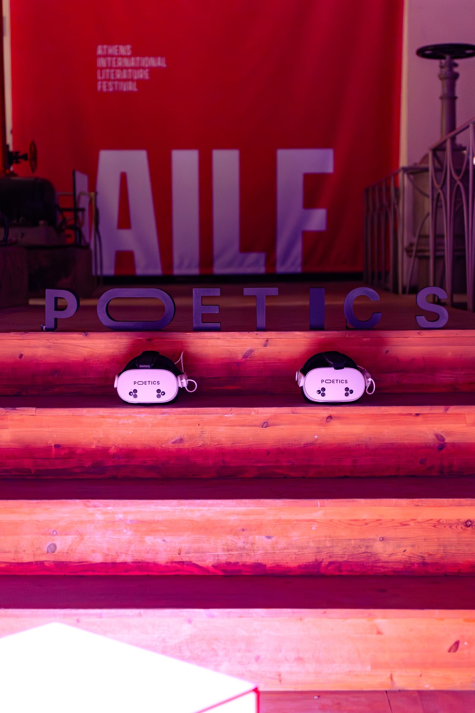 Two Poetics headsets on a wooden bench under the Athens International Literature Festival banner.