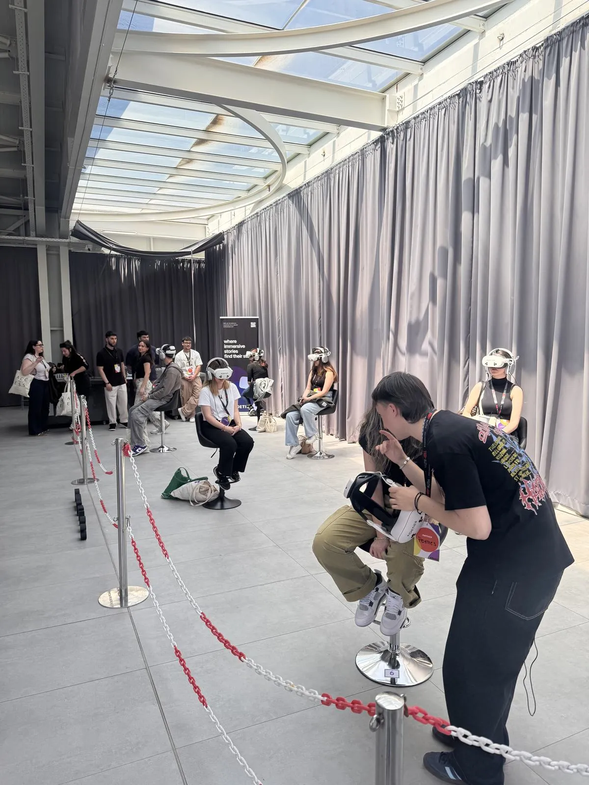 An audience queue and several Poetics VR stations in a bright event venue.