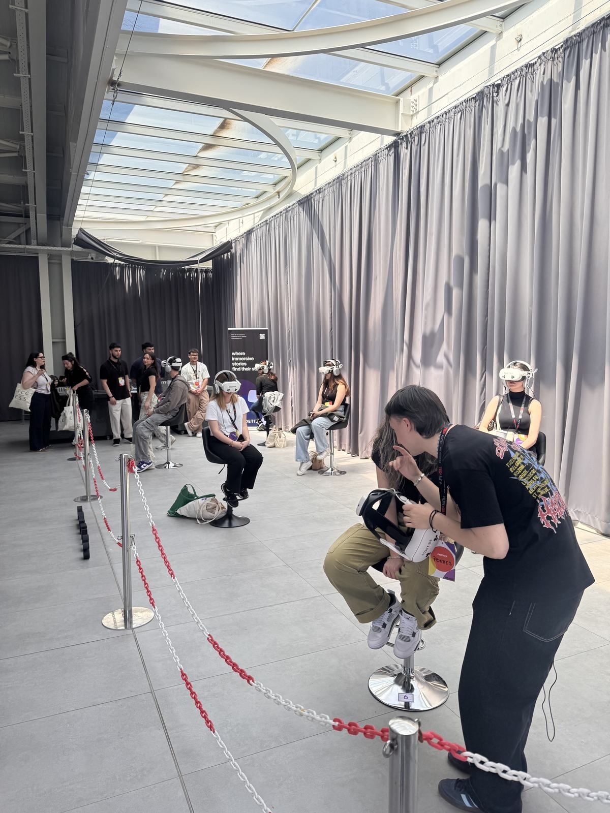 An audience queue and several Poetics VR stations in a bright event venue.