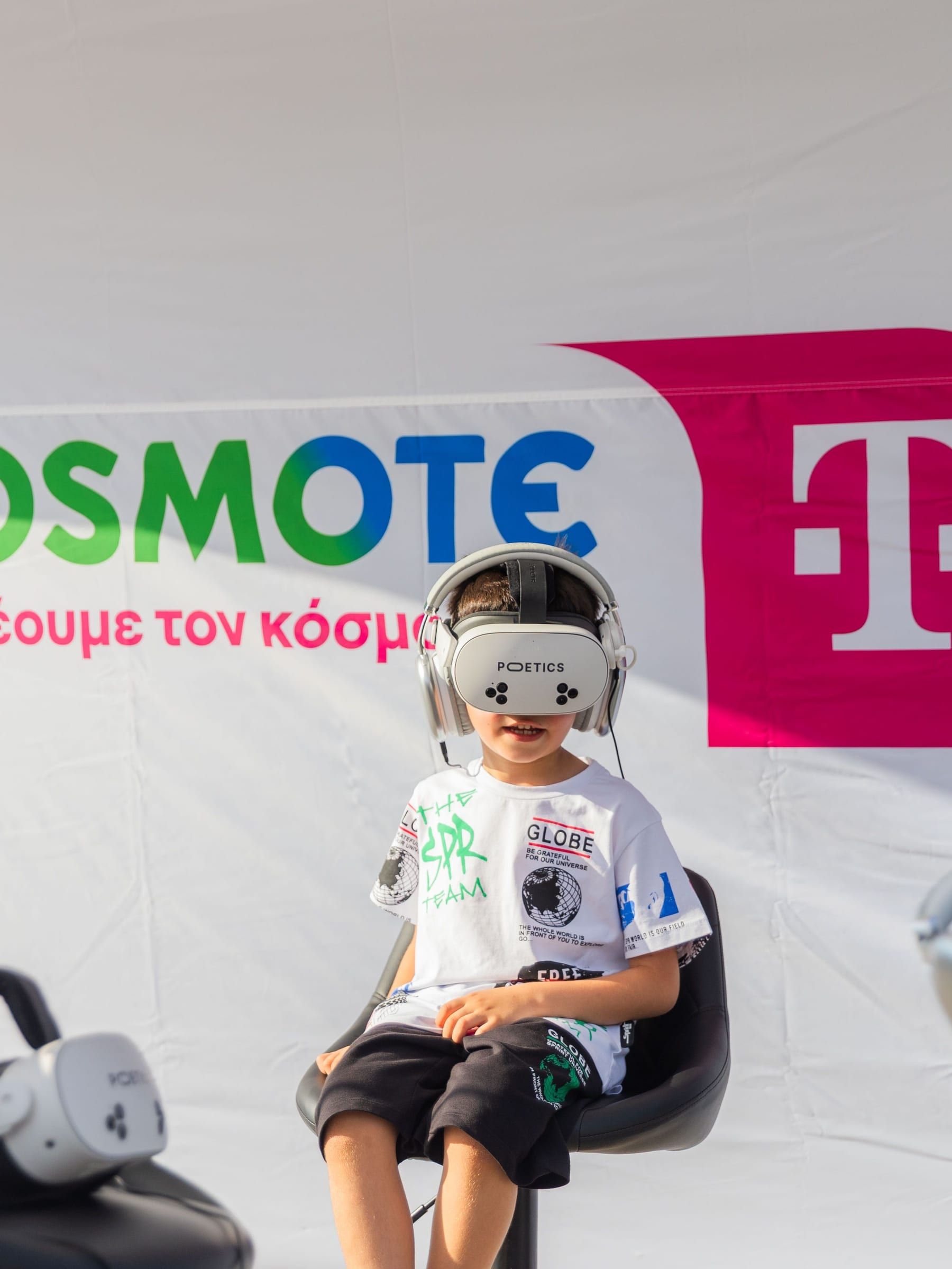 A child seated in a headset in front of the tent wall.