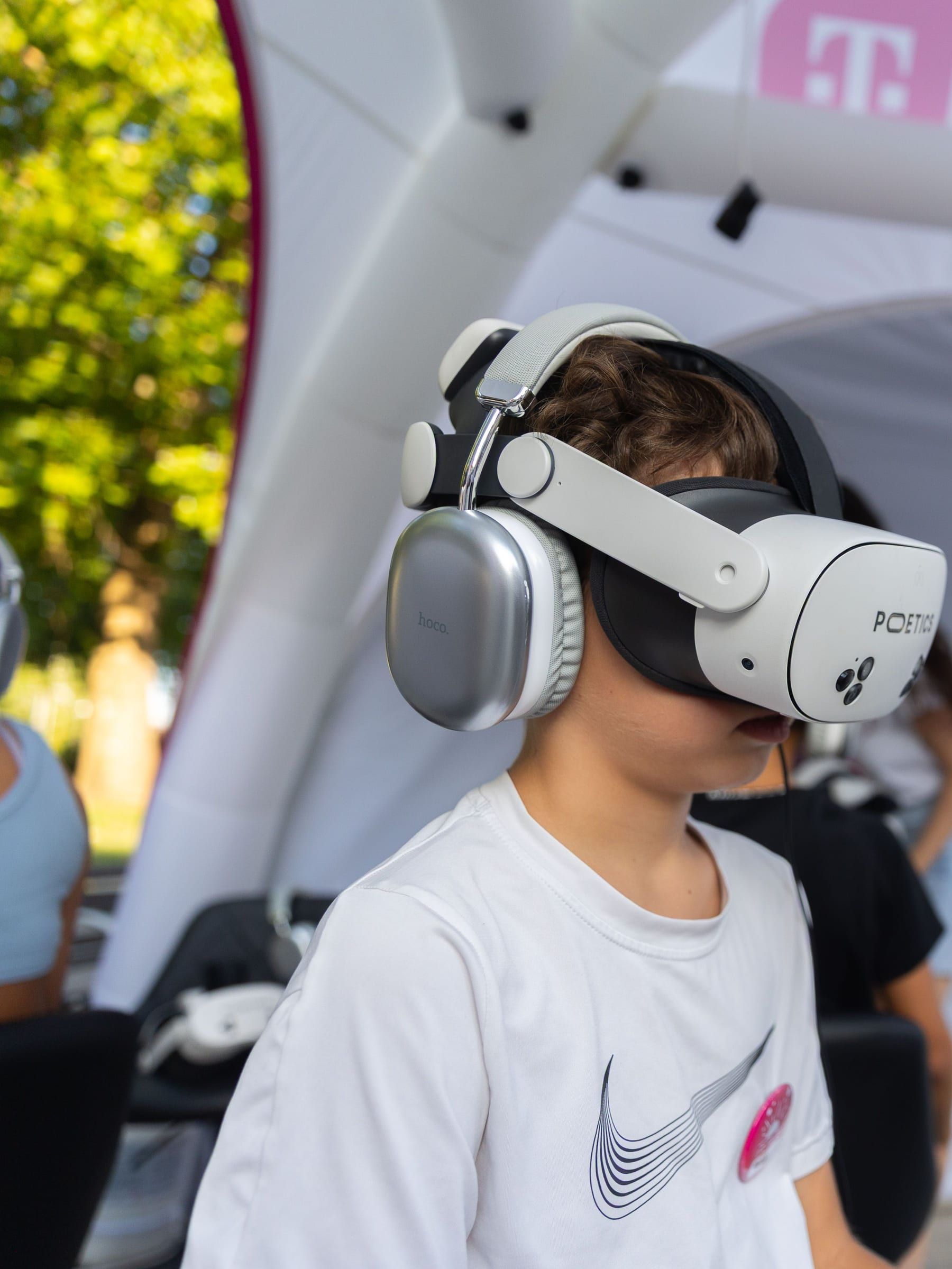 A child in a headset, seen in profile, in front of the tent.