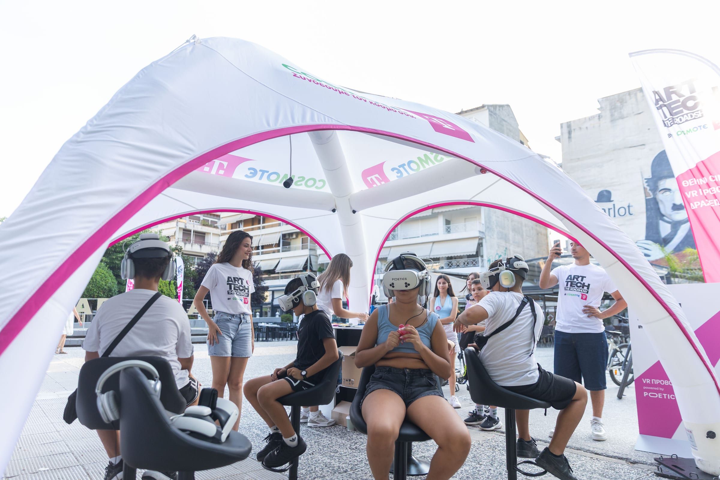 Visitors in headsets on swivel chairs under the roadshow tent, a staff member standing behind.