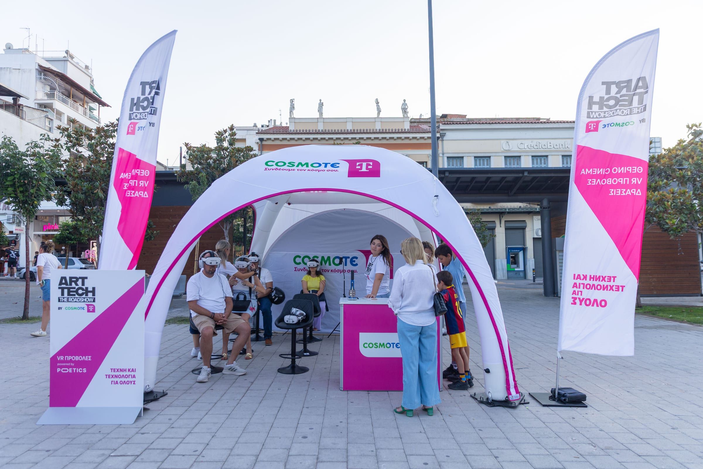 The Roadshow tent on a town square in Lamia, with banners and visitors at the stations.