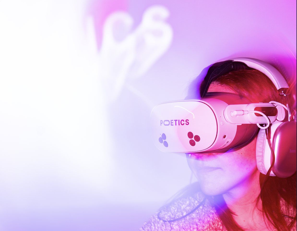 A visitor in a Poetics headset and headphones, lit in pink and violet.